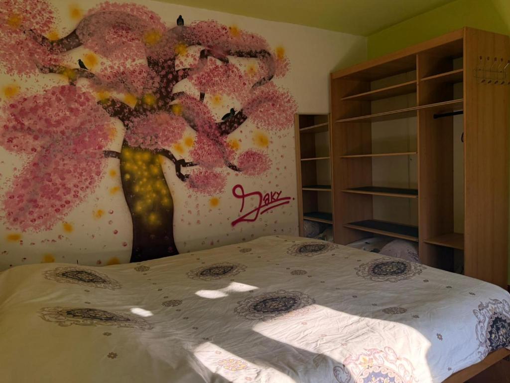 een slaapkamer met een muurschildering van een boom met roze bloemen bij Popasul din Valea Mare in Caransebeş