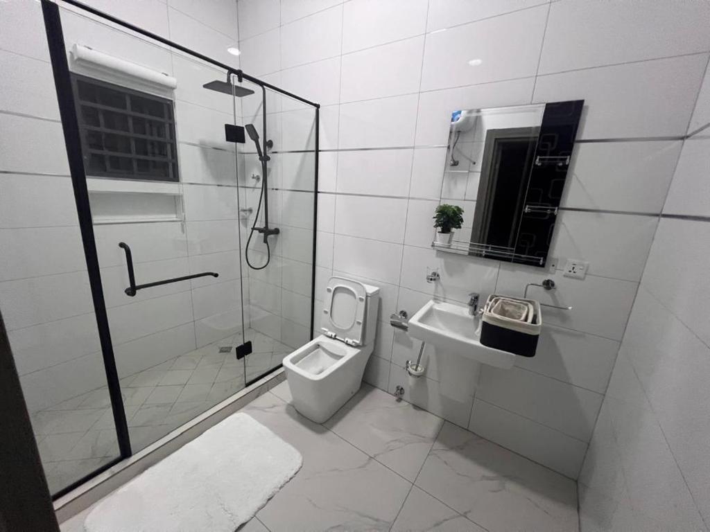 een badkamer met een douche, een toilet en een wastafel bij Akyamaa's Place Apartments in Accra