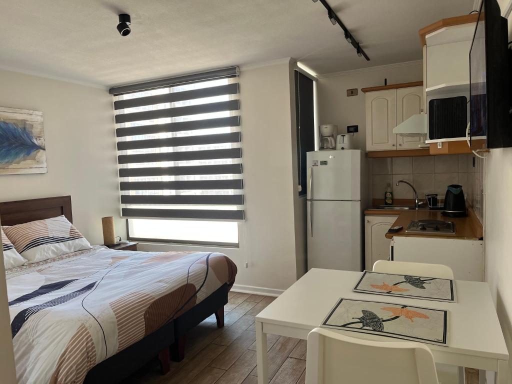ein Schlafzimmer mit Bett und Tisch und eine Küche in der Unterkunft Studio Cochrane in Santiago
