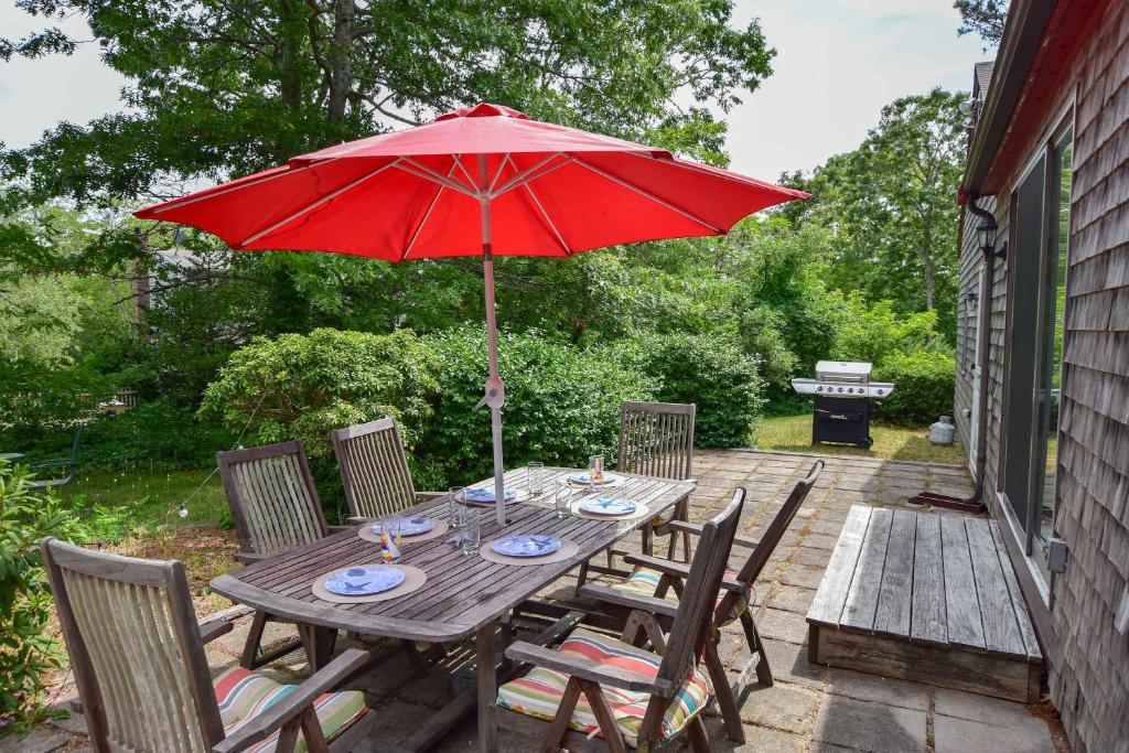 een houten tafel met een rode parasol op een patio bij Spacious Home w Finished Game Room in Eastham