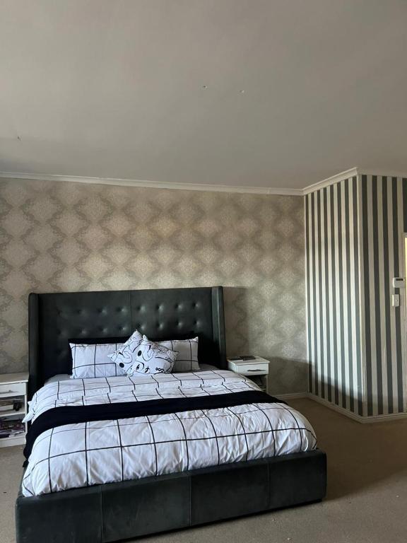 a bedroom with a large bed with a black headboard at Sleep easy at Peperboom in Kuilsrivier