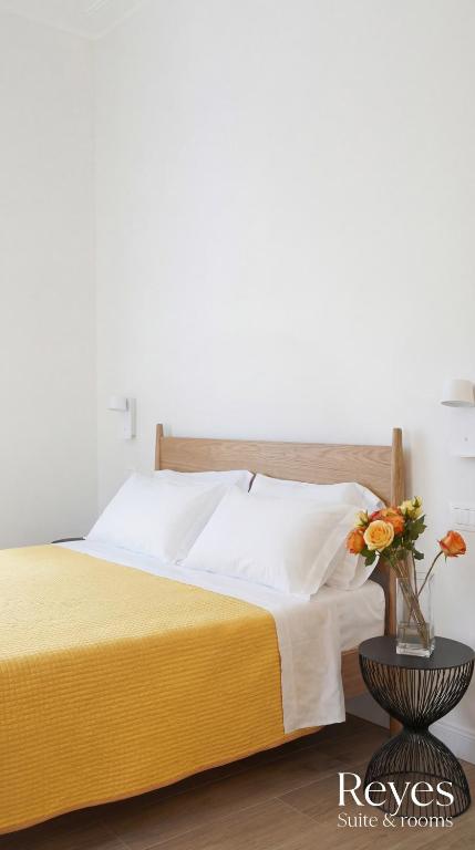 un letto con una coperta gialla e un vaso con fiori di Reyes Suite & Rooms a Roma