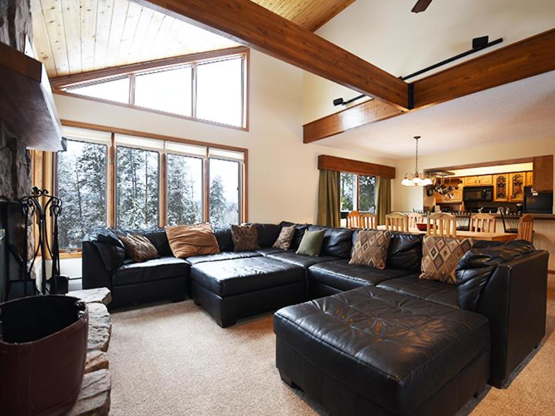 a living room with a black leather couch and a kitchen at 61 Jabberwocky Home by Stay Winter Park in Fraser