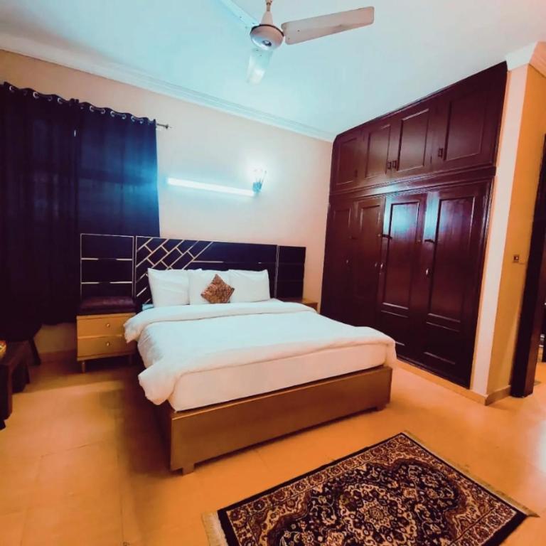 a bedroom with a large bed and wooden cabinets at Urban Suites in Faisalabad