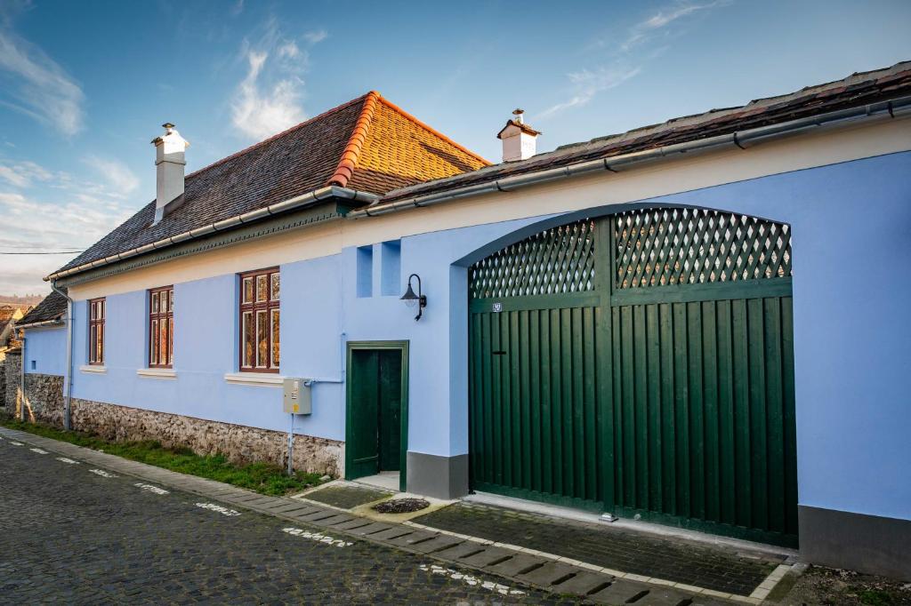 a white house with a green gate on a street at Curte la Munte - charming village house in Sebeşu de Sus