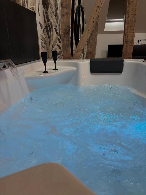 two wine glasses in a tub with blue water at Résidence ARTHUS Thamarys in Pierrefonds