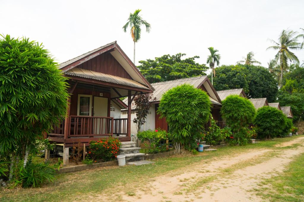 uma casa ao lado de uma estrada de terra com palmeiras em Weekender Bungalow em Lamai