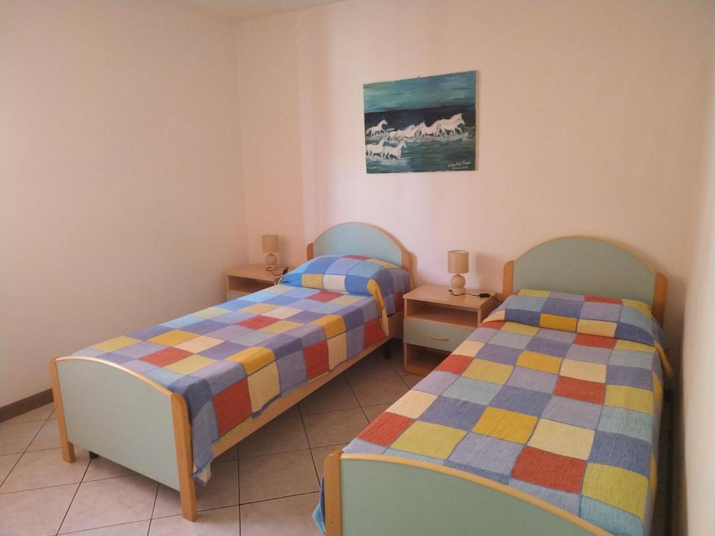 twee bedden in een kleine kamer met twee tafels bij Lungomare 2 in Porto Alabe