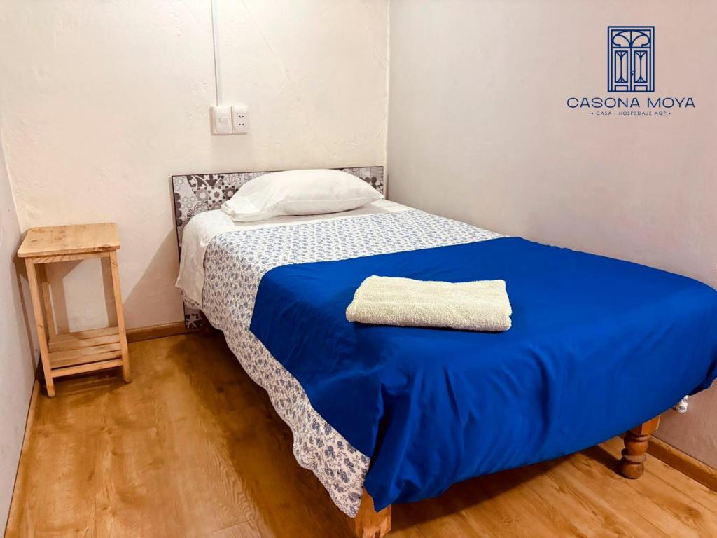 ein kleines Schlafzimmer mit einem Bett mit einer blauen Decke in der Unterkunft Casona Moya in Arequipa