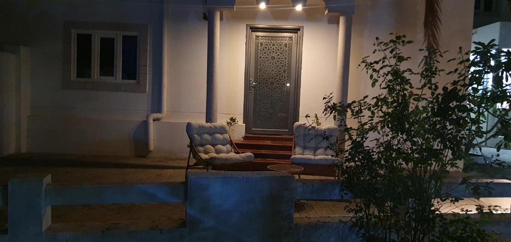 zwei Stühle stehen nachts vor einem Haus in der Unterkunft Nizwa heart garden home in Nizwa