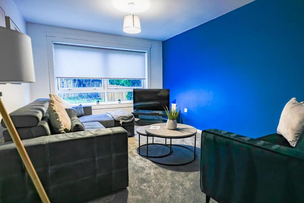 een blauwe woonkamer met een bank en een tafel bij Sedgebank House in Uphall