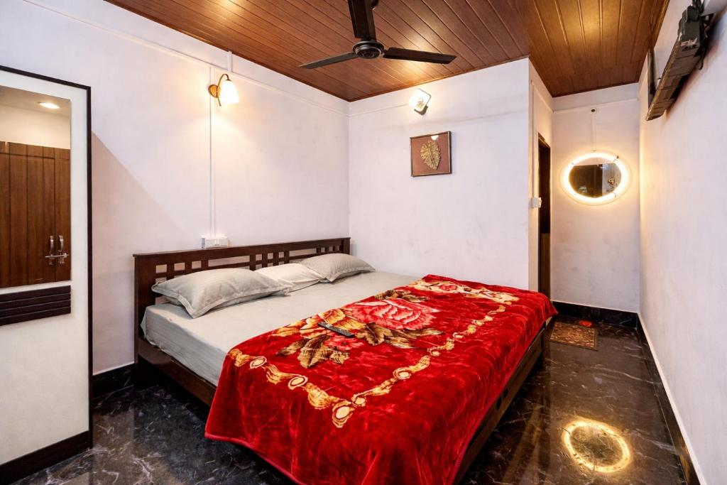 a bedroom with a bed with a red blanket at Dream Garden Homestay in Madikeri
