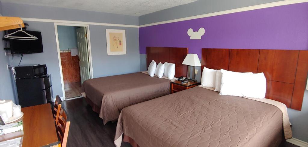 ein Hotelzimmer mit zwei Betten und einer lila Wand in der Unterkunft Riviera Motel in Anaheim
