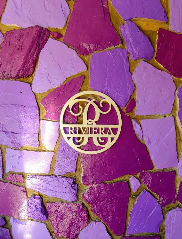 a purple stone wall with a logo on it at Riviera Motel in Anaheim