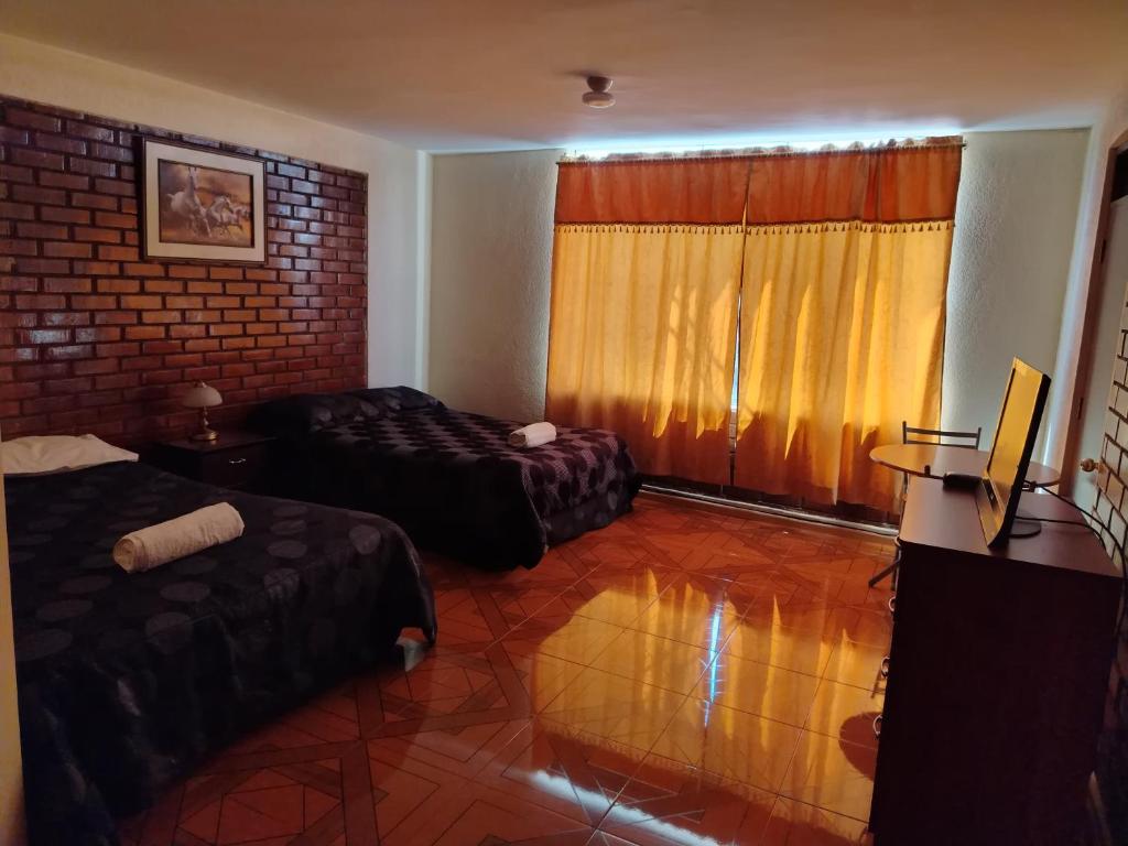 een hotelkamer met twee bedden en een raam bij Asvea INN in Arequipa