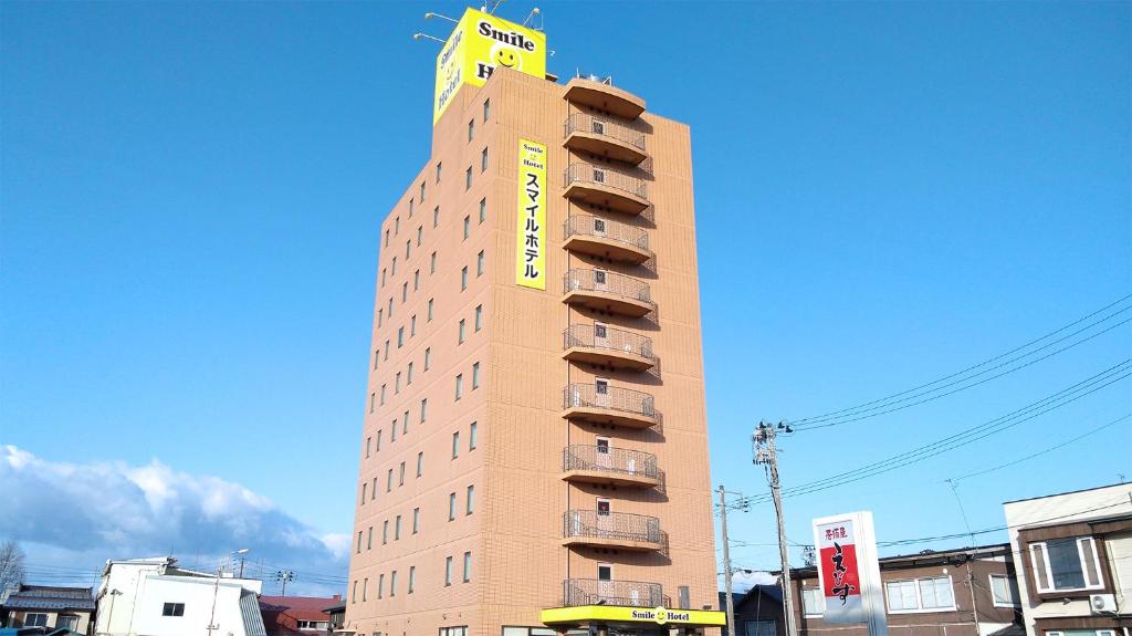 un edificio alto con un cartello giallo sopra di Smile Hotel Towada a Towada
