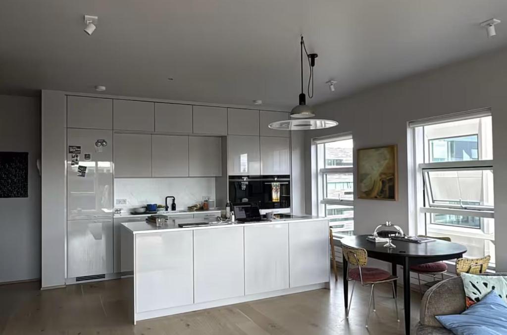 una cucina con armadi bianchi e un tavolo di Room in modern downtown apt with private bathroom a Reykjavik