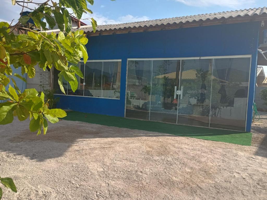 a blue building with glass windows on the side at Casa do refúgio melhor para suas férias in Palhoça