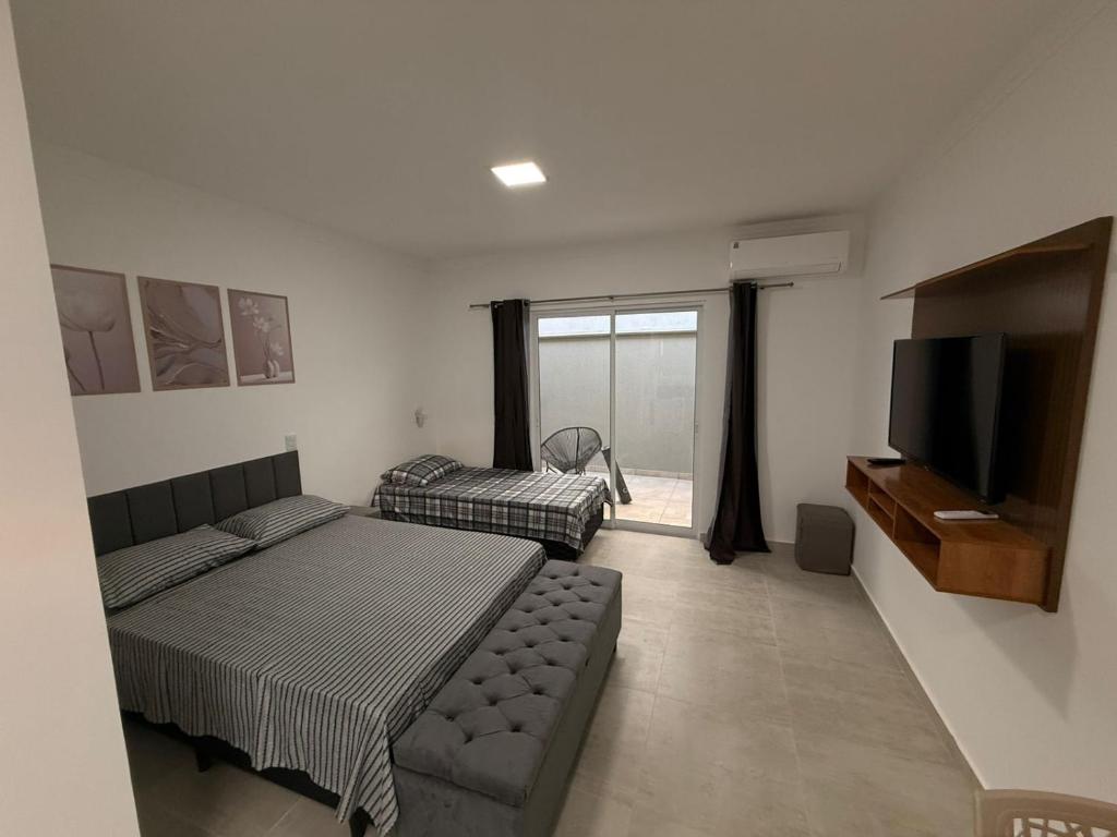 een slaapkamer met een bed, een bank en een flatscreen-tv bij Flats Privativos MaragoJulios in Maragogi