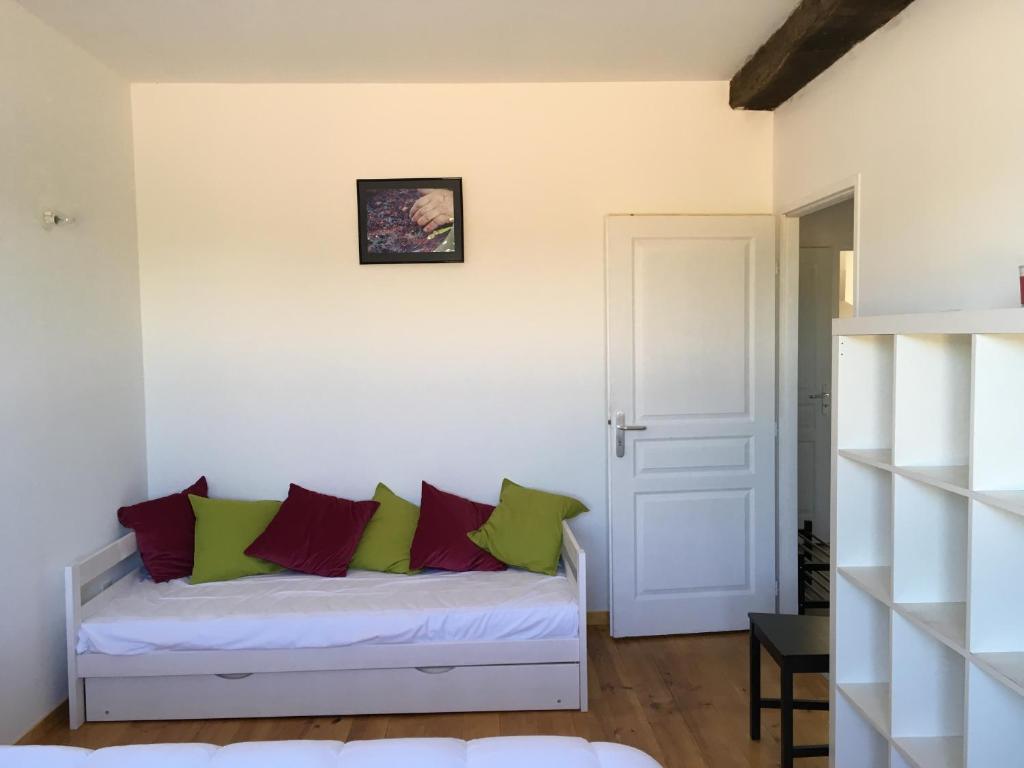Domaine de Montels في Albias: غرفة مع أريكة بيضاء مع وسائد خضراء وأحمر