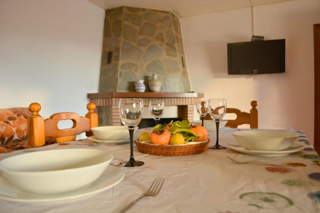 a table with plates and wine glasses and a basket of fruit at Casa rural en Granada in Atarfe