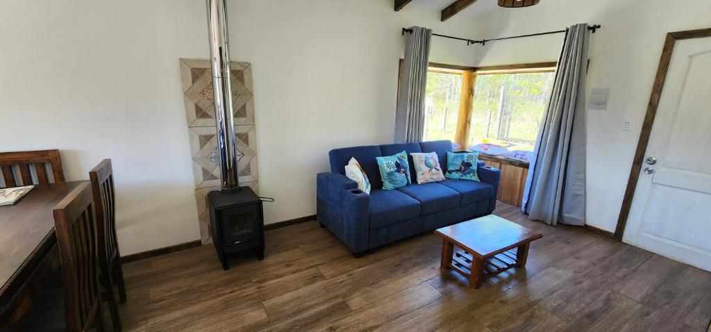 un soggiorno con divano blu e stufa a legna. di Cabañas Puelche a Liquiñe