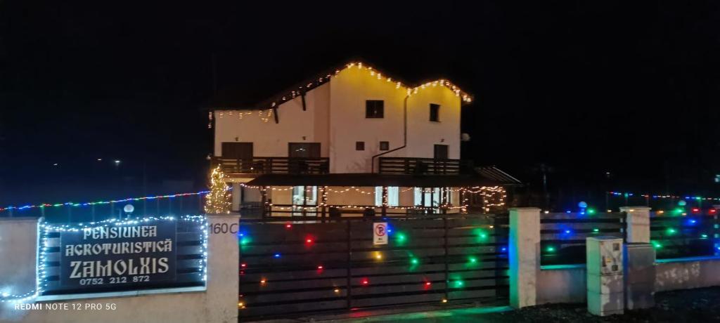 ein mit Weihnachtslichtern geschmücktes Haus mit einem Schild in der Unterkunft AGROPENSIUNEA ZAMOLXIS in Costeşti