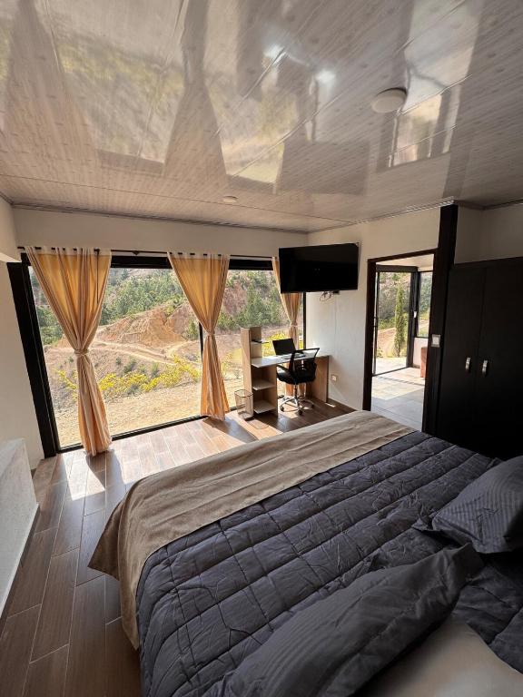 ein Schlafzimmer mit einem großen Bett und einem großen Fenster in der Unterkunft Glamping Eclipse Mirador Jarana Villa de Leyva 