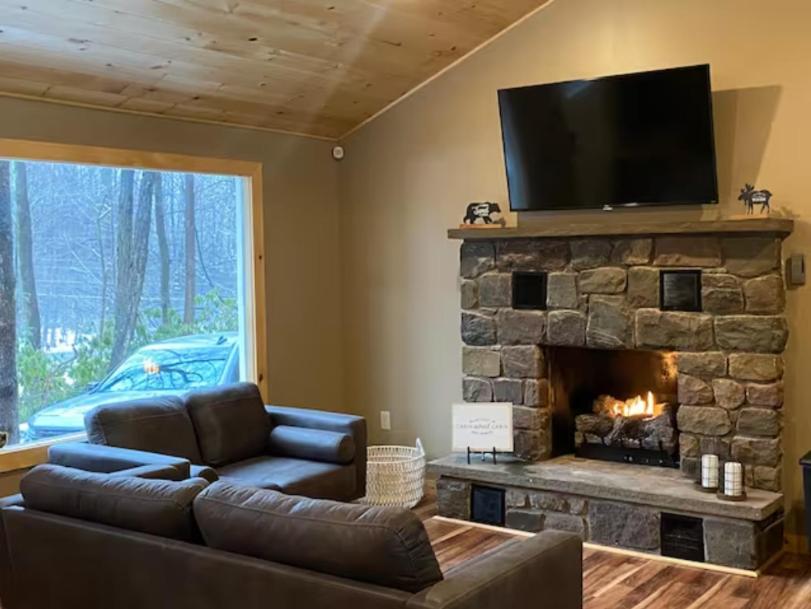 un soggiorno con divano e camino in pietra di Sullivan Trail Cottage a Tannersville