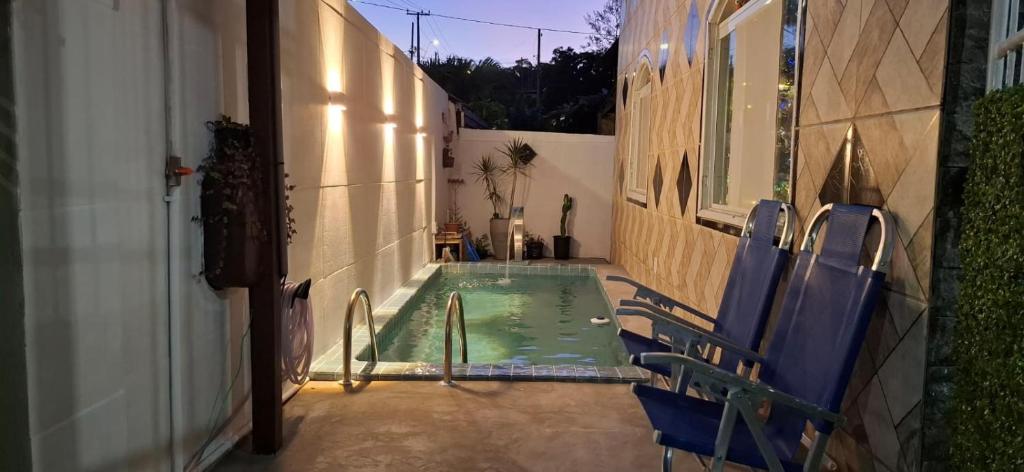 una piccola piscina con sedie blu accanto a un edificio di Brachil 1 a Búzios