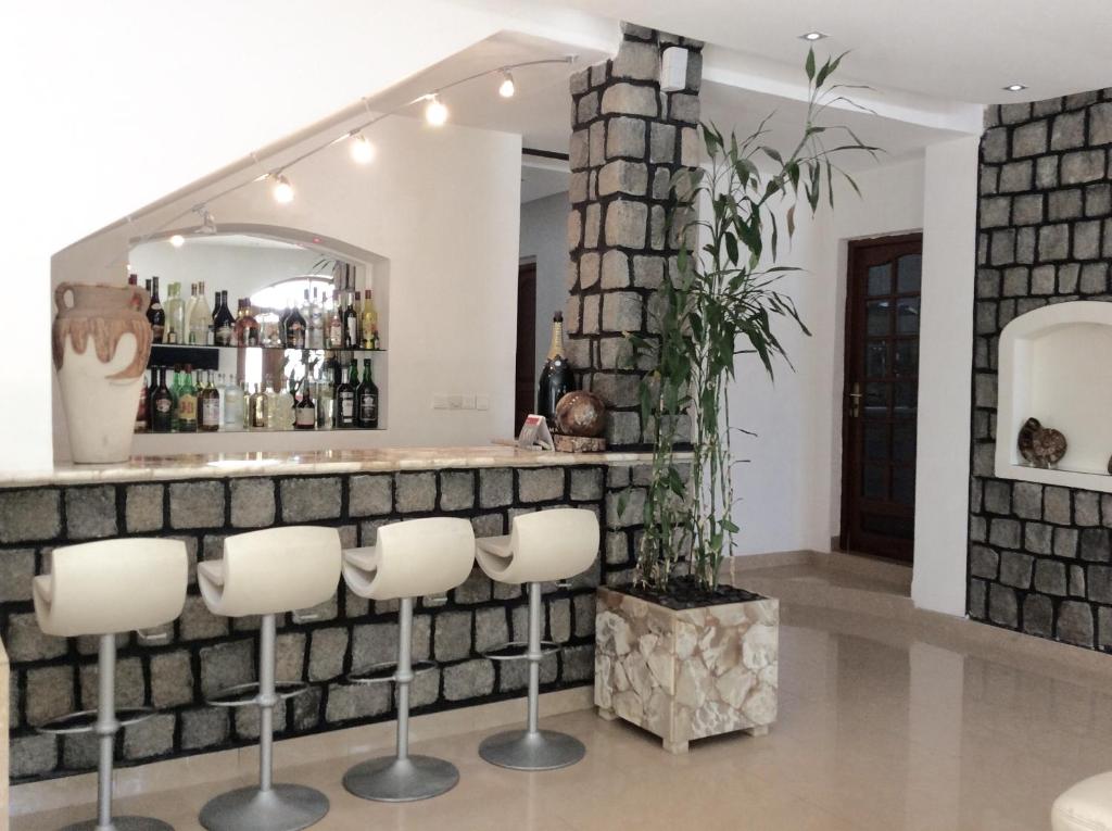 a bar with white stools in front of a brick wall at Villa Perle Noire in Ambatoloaka