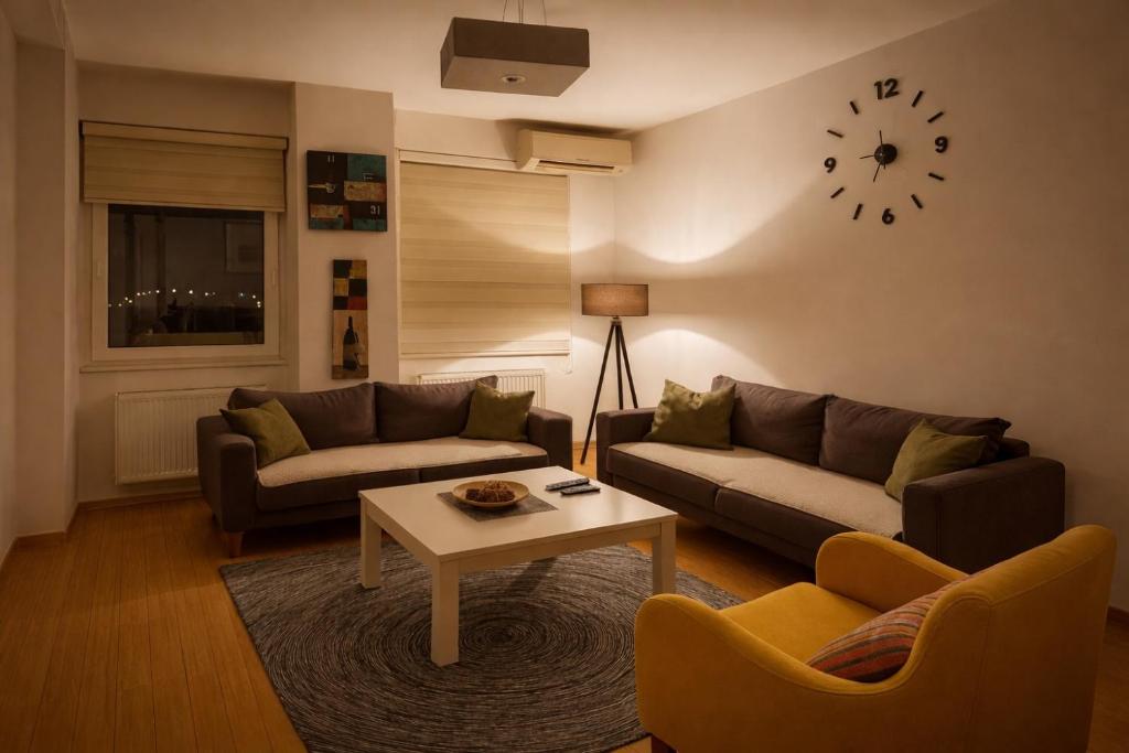 een woonkamer met een bank, een tafel en een klok bij London apartments 2 in Pristina