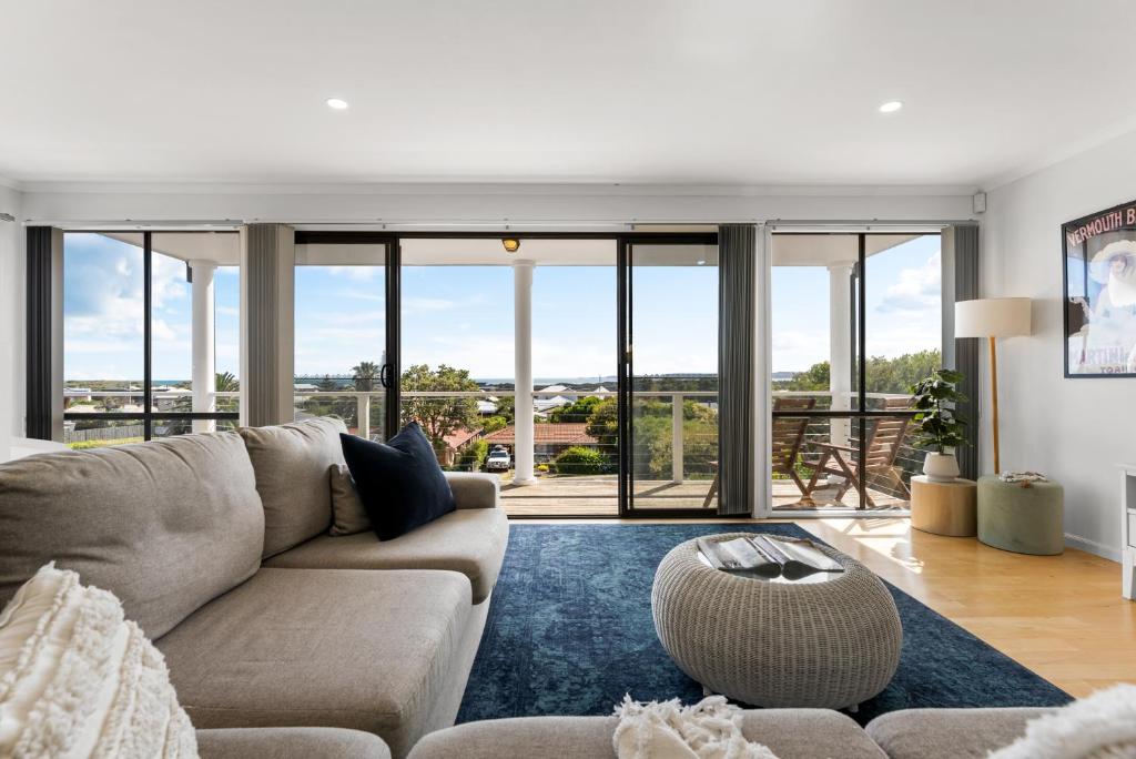 a living room with a couch and large windows at Hazel Beach House - Ocean Views & Coastal Charm in Goolwa South