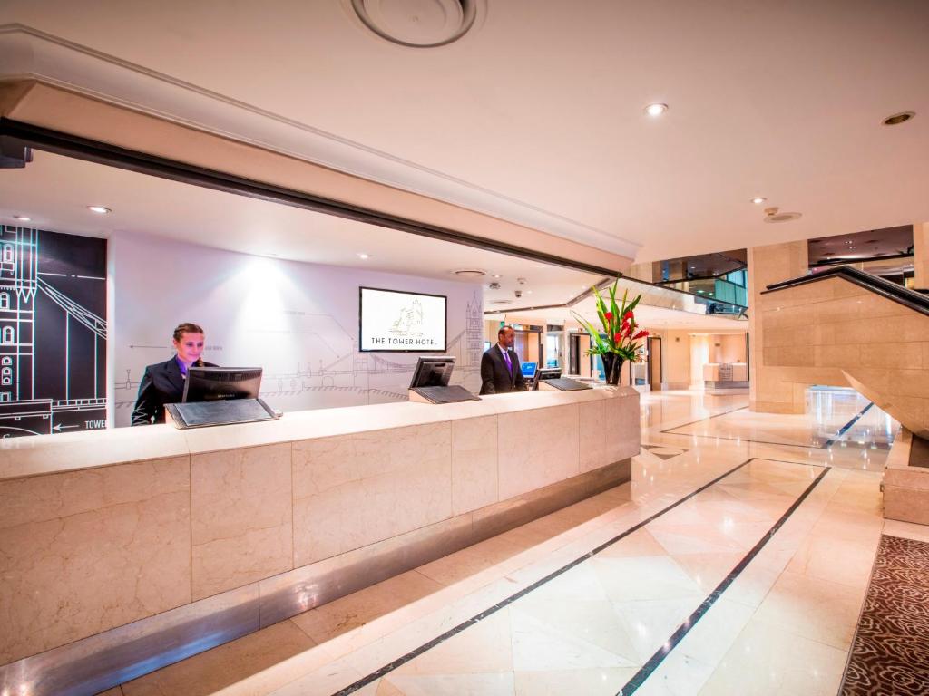 a lobby with two men sitting at a reception counter at The Tower Hotel, by Thistle in London