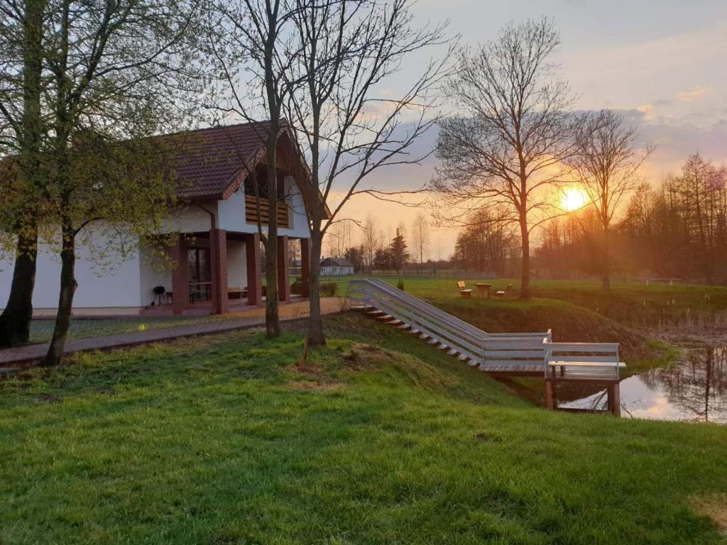 KodeńSielsko Anielsko Zabłocie的夕阳西下，池塘边的一栋建筑。