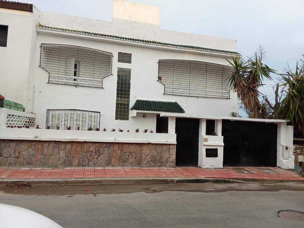 a white house with two windows and a garage at Villa harhora in Temara