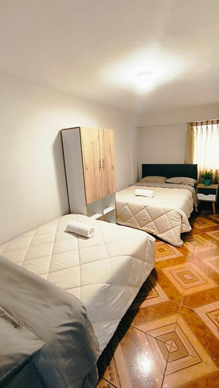 three beds in a room with wooden floors at Laguna Apartment in Huaraz