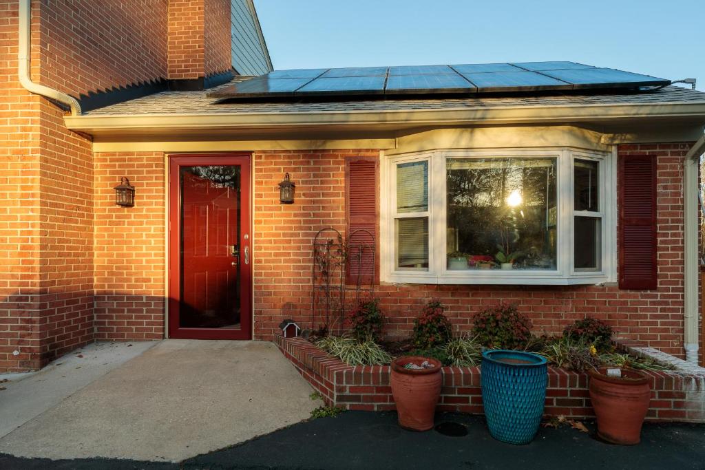 a brick house with a red door and potted plants at Bright, Spacious Home with Private Deck in Potomac
