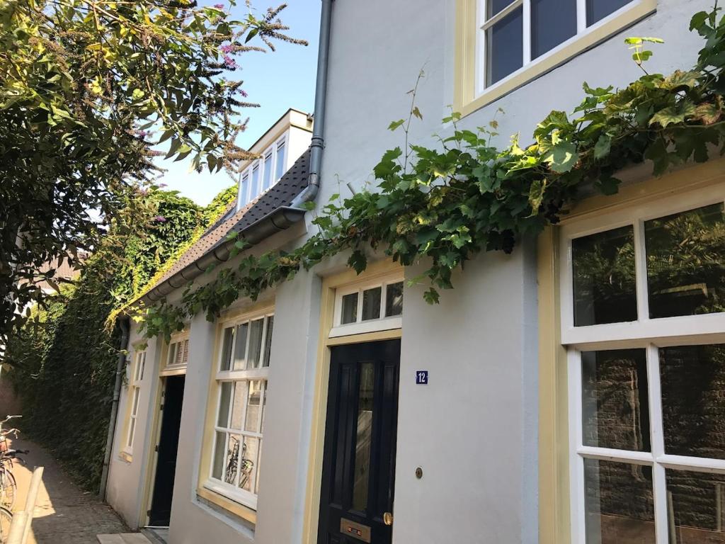 a white house with a black door and windows at Unique tranquil spot with garden, centre Den Bosch in Den Bosch