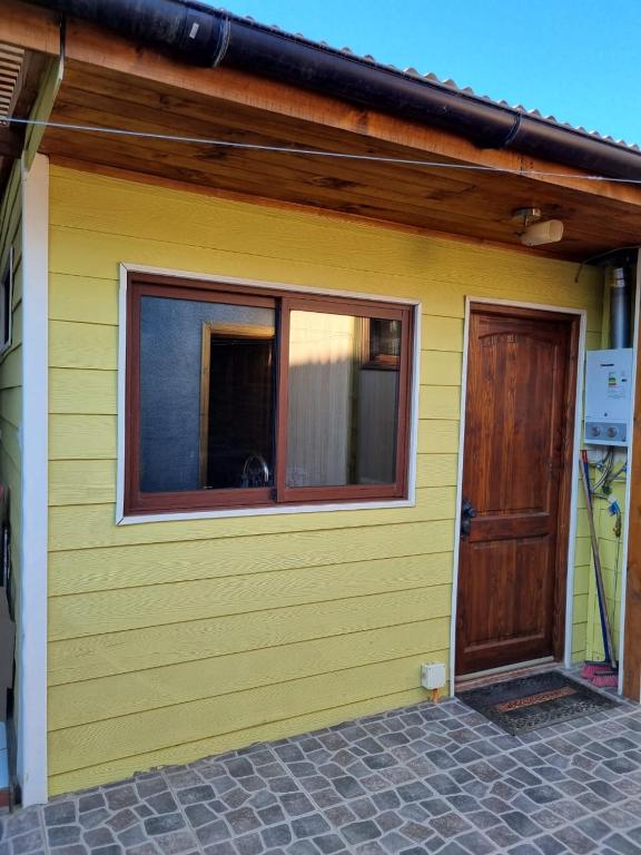 een geel huis met een raam en een deur bij Departamento Mar y Viento in Pichilemu