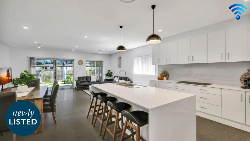 een keuken met witte kasten en een keukeneiland met stoelen bij Bella Callala in Callala Beach