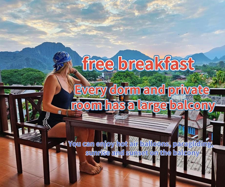 een vrouw zittend op een bankje op een balkon bij west water hostel in Vang Vieng