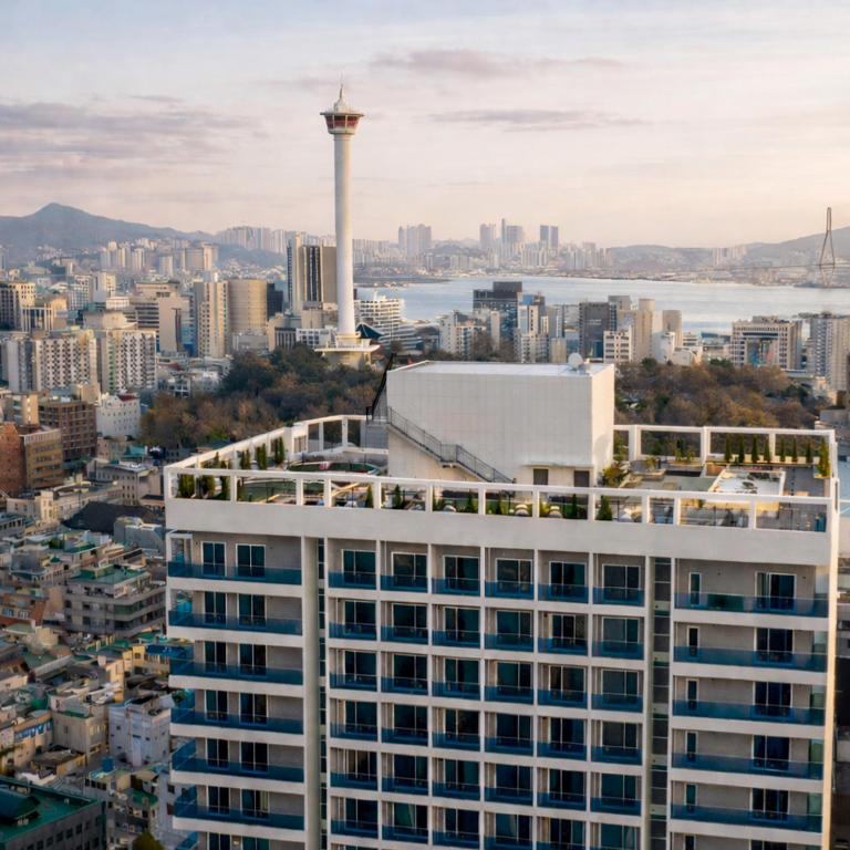 a city skyline with a tall white building and a tower at Magnum Nampo Hotel in Busan