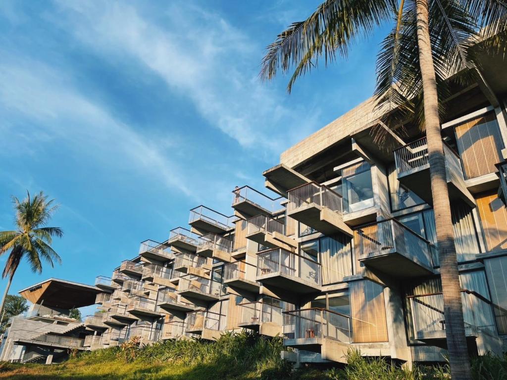a building with windows and a palm tree at Varivana Resort Koh Phangan, The Centara Collection in Thong Sala