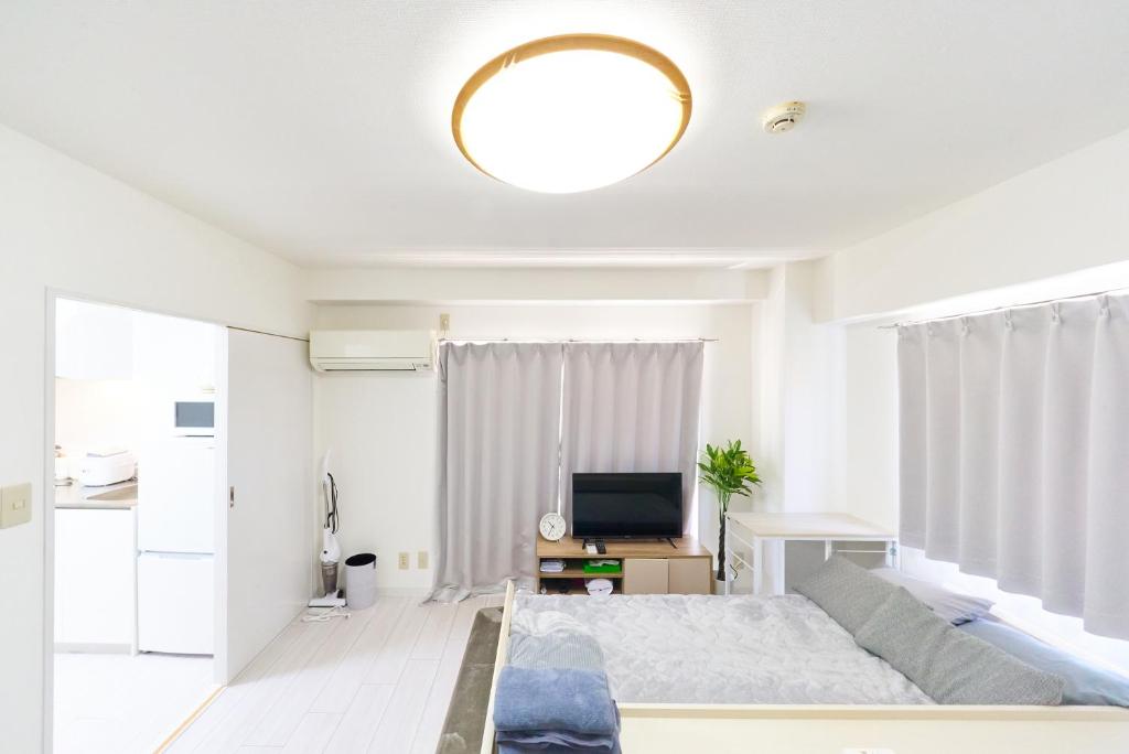 a white bedroom with a bed and a television at Maison Junes 21 in Tokyo