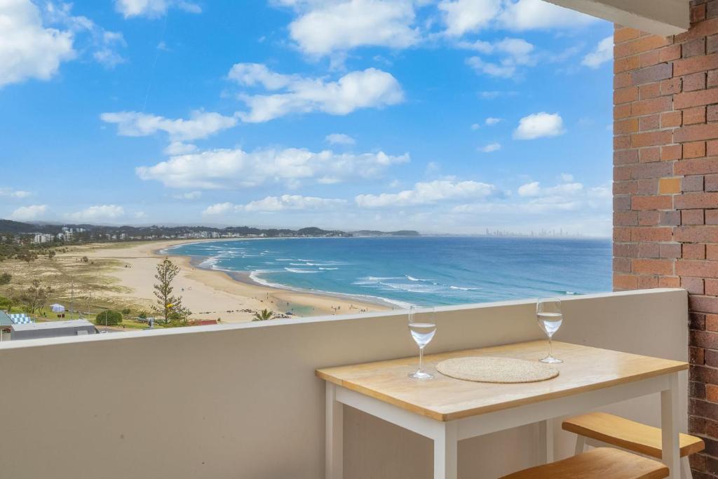 een balkon met een tafel met 2 wijnglazen bij Bel R Vista in Gold Coast