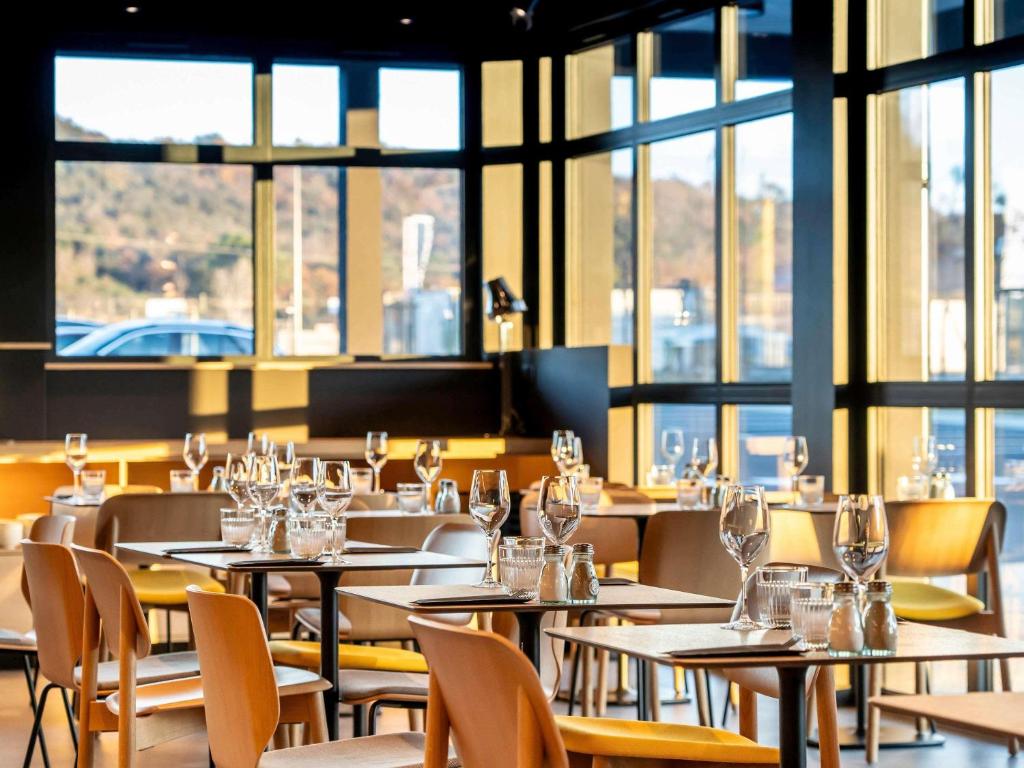 een restaurant met tafels, stoelen en ramen bij ibis Saint Paul Trois Chateaux in Saint-Paul-Trois-Châteaux