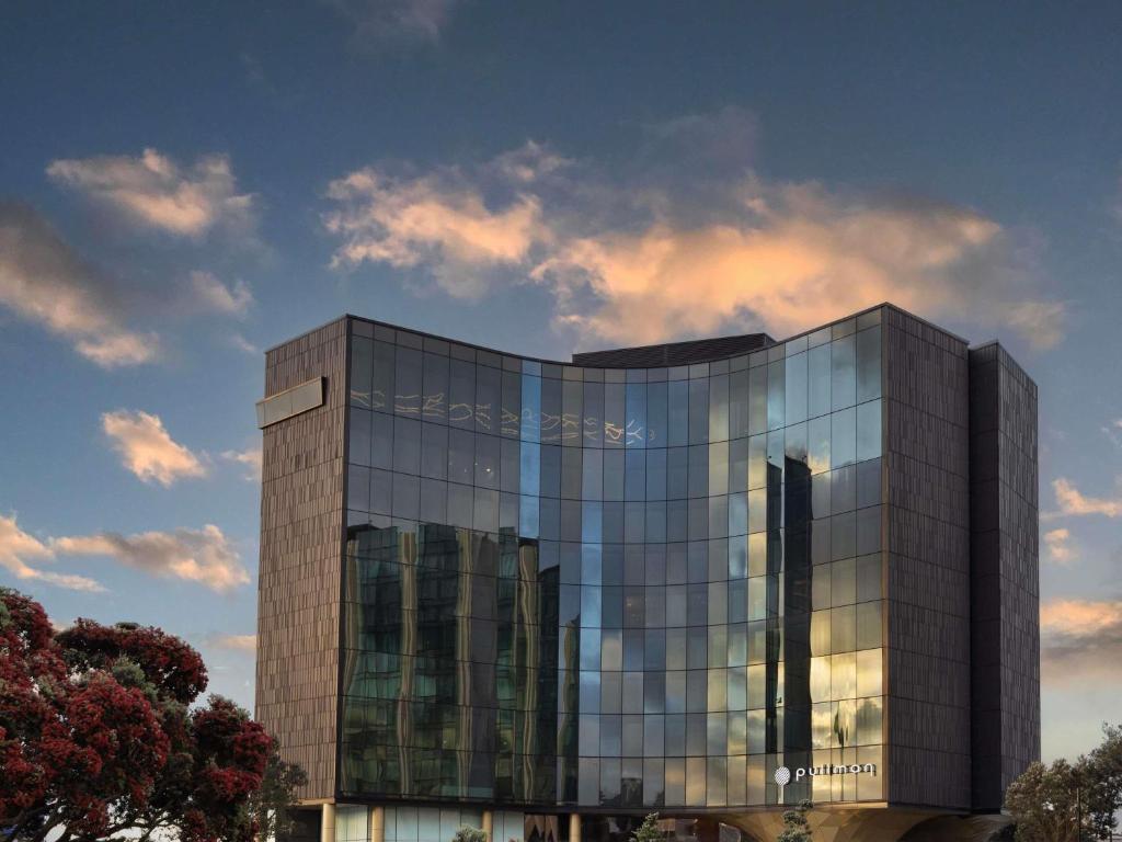 un grand bâtiment en verre avec beaucoup de fenêtres dans l'établissement Pullman Auckland Airport, à Auckland