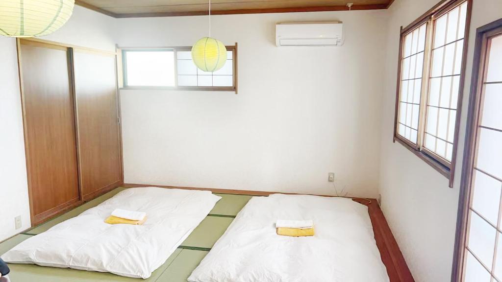 zwei Betten in einem Zimmer mit zwei Fenstern in der Unterkunft 富士見旅館206 in Fujiyoshida