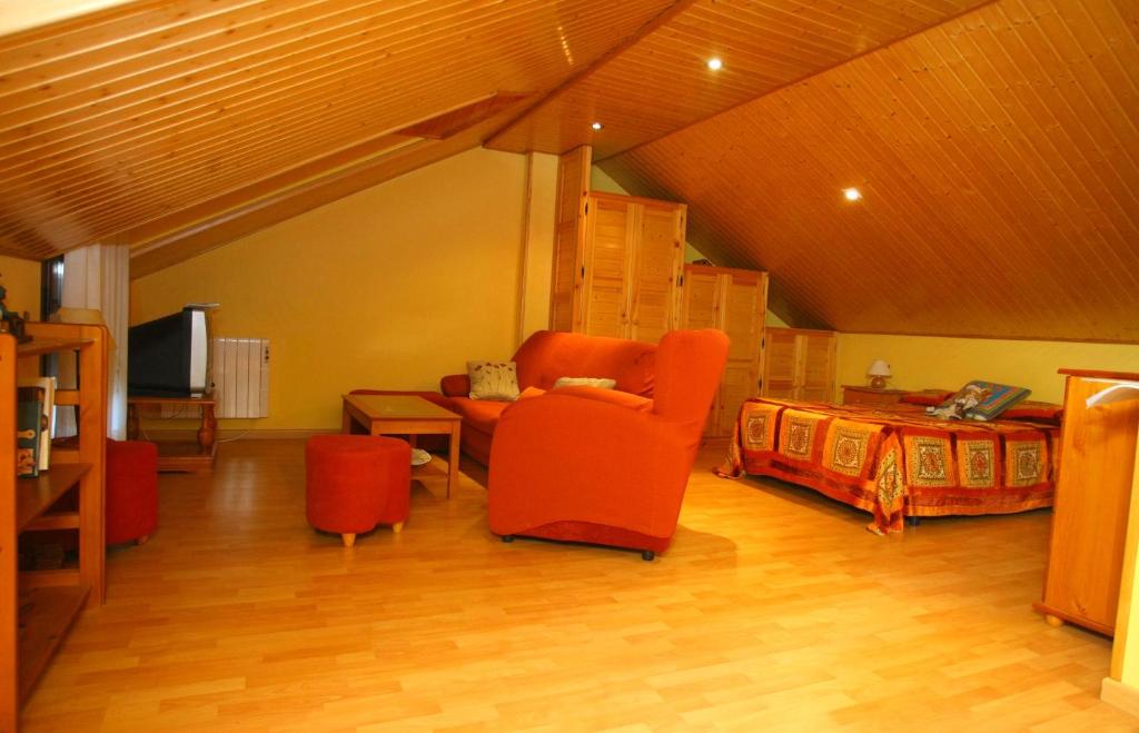 a living room with red chairs and a bed at Casa de Abril 1 in San Cristóbal de Valdueza